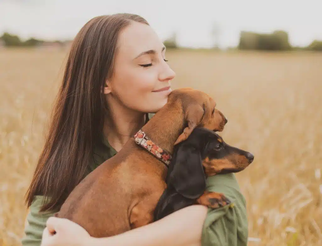 pet owner hugs her wiener dogs