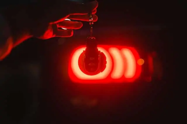 An auto locksmith holding a red key chain in the dark.