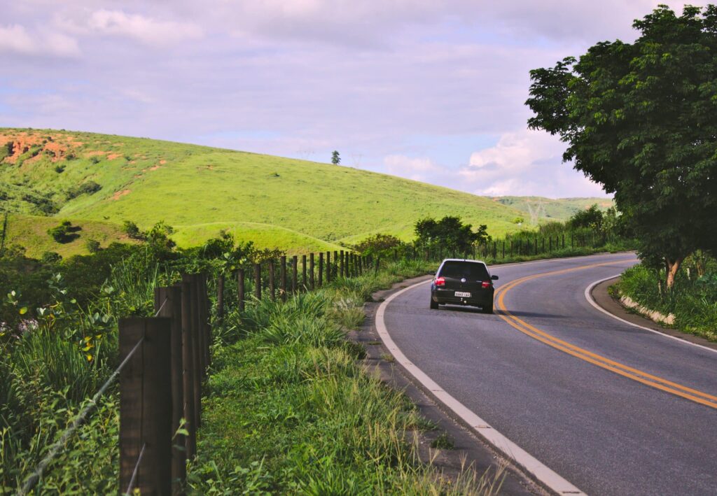 An insured black car drives on the road.