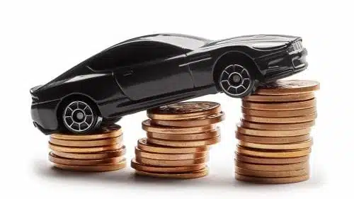 Car model over a lot of money stacked coins on white background. You may have to pay car insurance excess