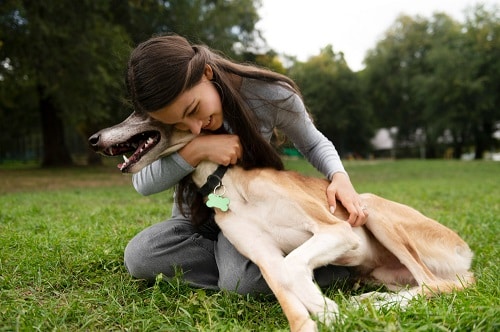 smiley woman hugging dog for random acts of kindness day. You can help animals by volunteering at a shelter
