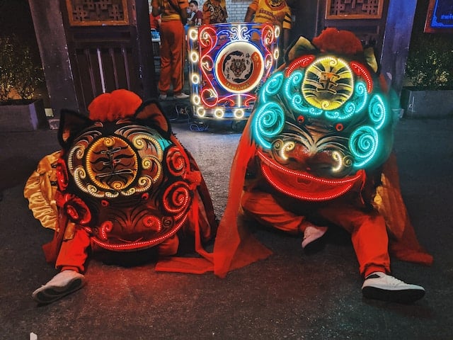 Two Chinese dancers dressed in colorful costumes celebrate the "Chinese New Year" with vibrant outfits inspired by the "Year of the Dragon" in the Chinese zodiac.