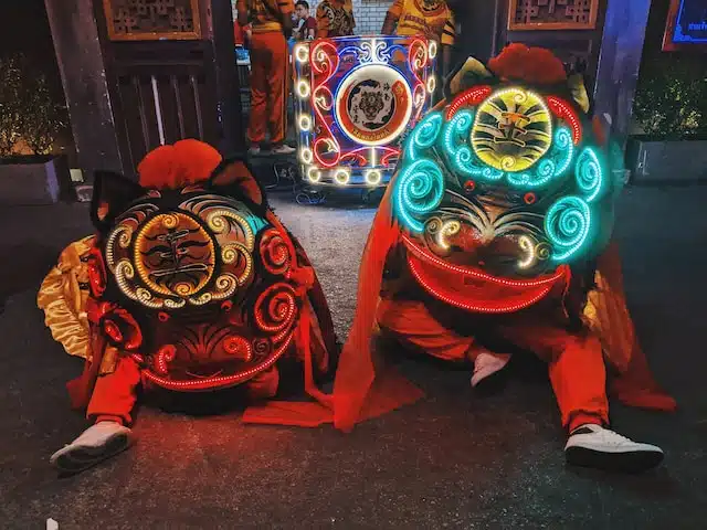 Two Chinese dancers dressed in colorful costumes celebrate the "Chinese New Year" with vibrant outfits inspired by the "Year of the Snake" in the Chinese zodiac.