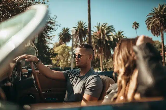 A man in sunglasses driving a convertible. Are convertible cars worth it? You have to weigh up the pros and cons of convertibles before making that decision