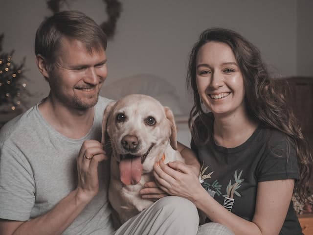 Pet owners pose for a photo with a happy dog who has recovered from anxiety disorder