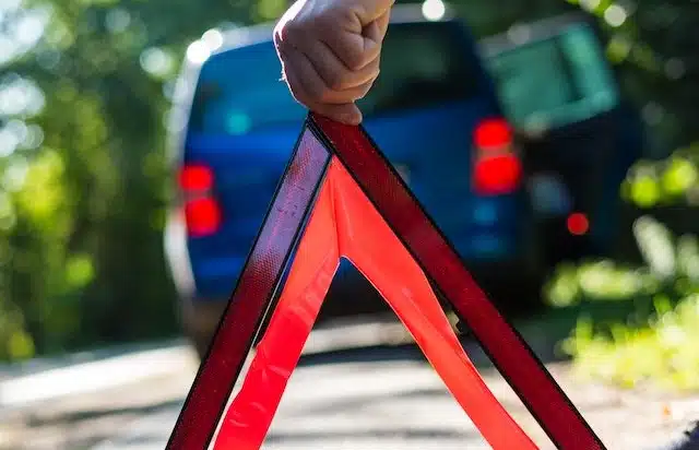 man puts up his emergency triangle after a car breakdown while waiting for roadside assistance