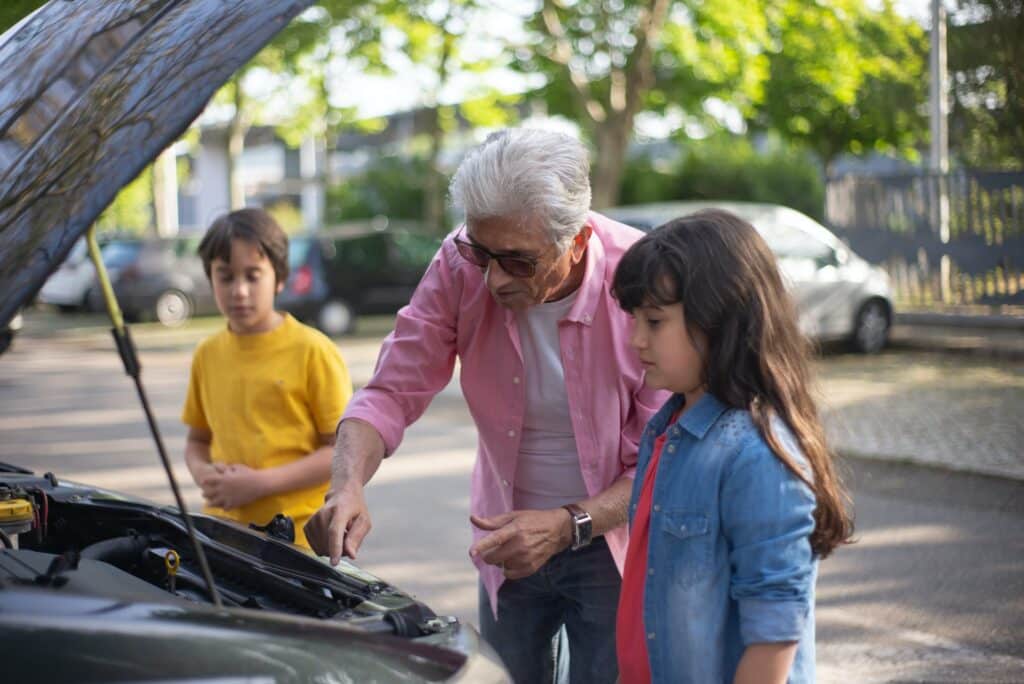 A grandfather shows his grandchildren how to conduct an essential car safety check before a driving holiday.