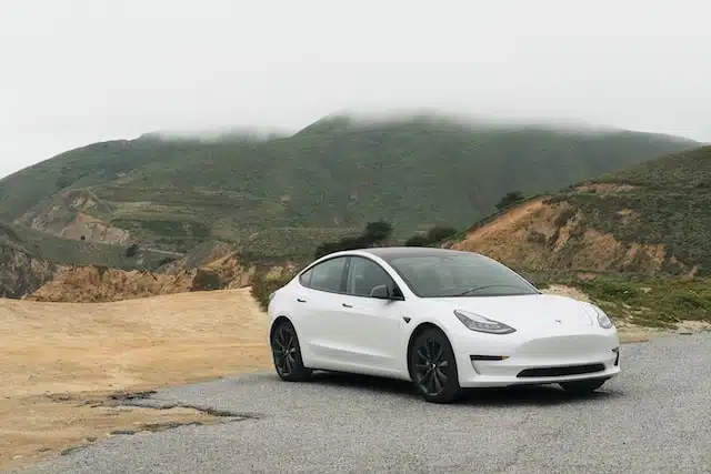 This image shows a Tesla parked on a road. the owner may be shopping for insurance for a tesla.