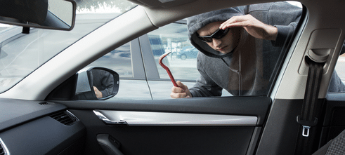 A thief looking into a car. We're talking about contents and car insurance in this blog