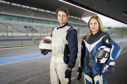 Motor cyclist and a race car driver posing in the pit box