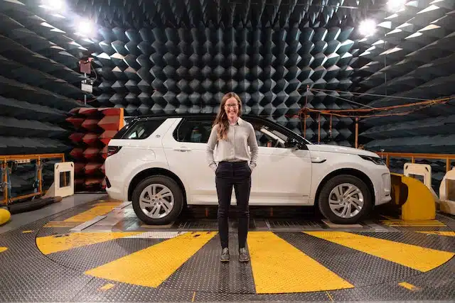 a woman stands in front of a safety tested car with high safety ratings that can count in favour of reducing the cost of car insurance
