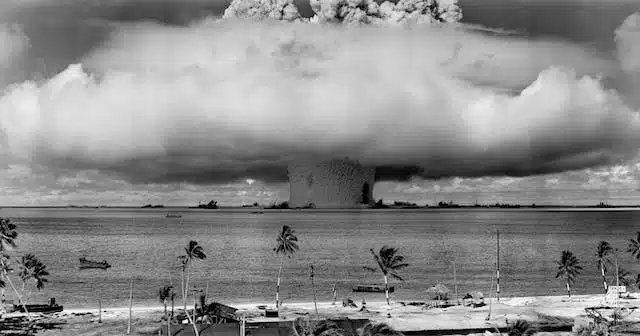 A black and white photo of a nuclear explosion over a beach, representing a force majeure event, meaning that certain insurance obligations will fall away considering the uncontrollable severity of the situation