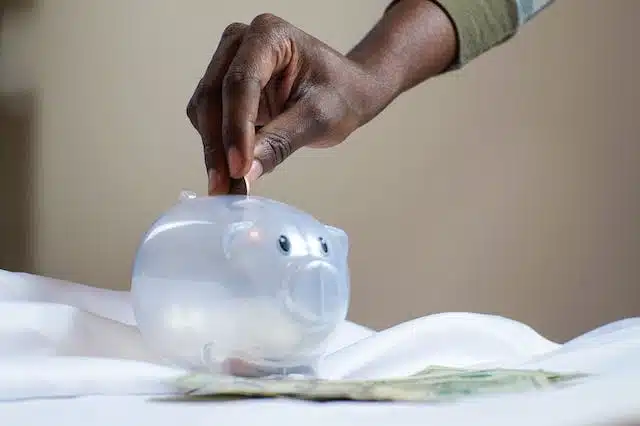 A hand putting money into a piggy bank.