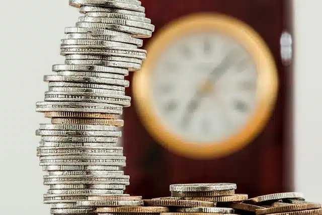A stack of cheap car insurance coins in front of a clock.