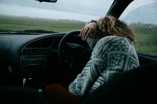 A woman sits in the driver's seat of a car, potentially engaging in drink driving.
