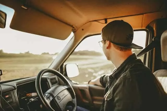 A man sitting in the driver's seat of a truck, contemplating car insurance options with a foreign licence.