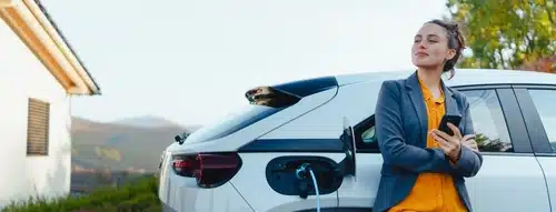 A woman standing next to an electric car which she was motivated to buy after learning about the electric car rebate scheme in Australia