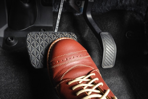 A brown shoe emerges as if stepping straight from the pages of top articles, pressing a car brake pedal with precision inside a vehicle.