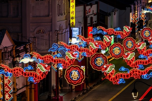 Colorful neon dragon lights illuminate the street at night with red and yellow hues, evoking the festive spirit of the Chinese New Year and celebrating the vibrant traditions of Chinese zodiac animals.