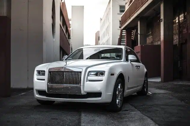 A luxurious white Rolls Royce elegantly parked in an alley.
