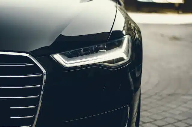 A black Audi Q7 with its headlights on, a luxury car subject to the Luxury Car Tax (LCT) threshold in Australia.