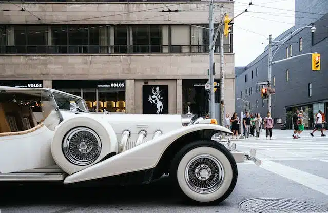 A vintage car is parked in the middle of the street.