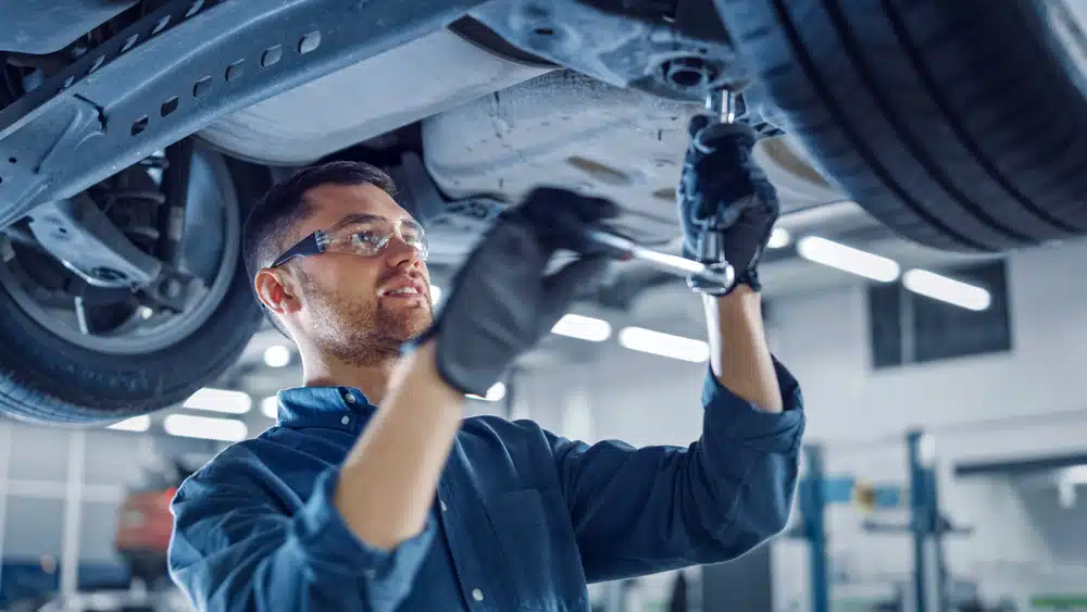 A mechanic performing a major car service in a garage.