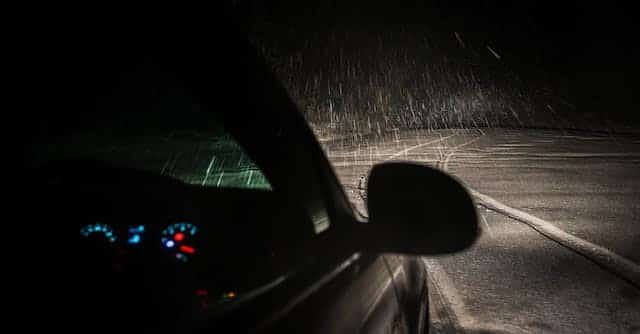 A car driving on a rainy road at night