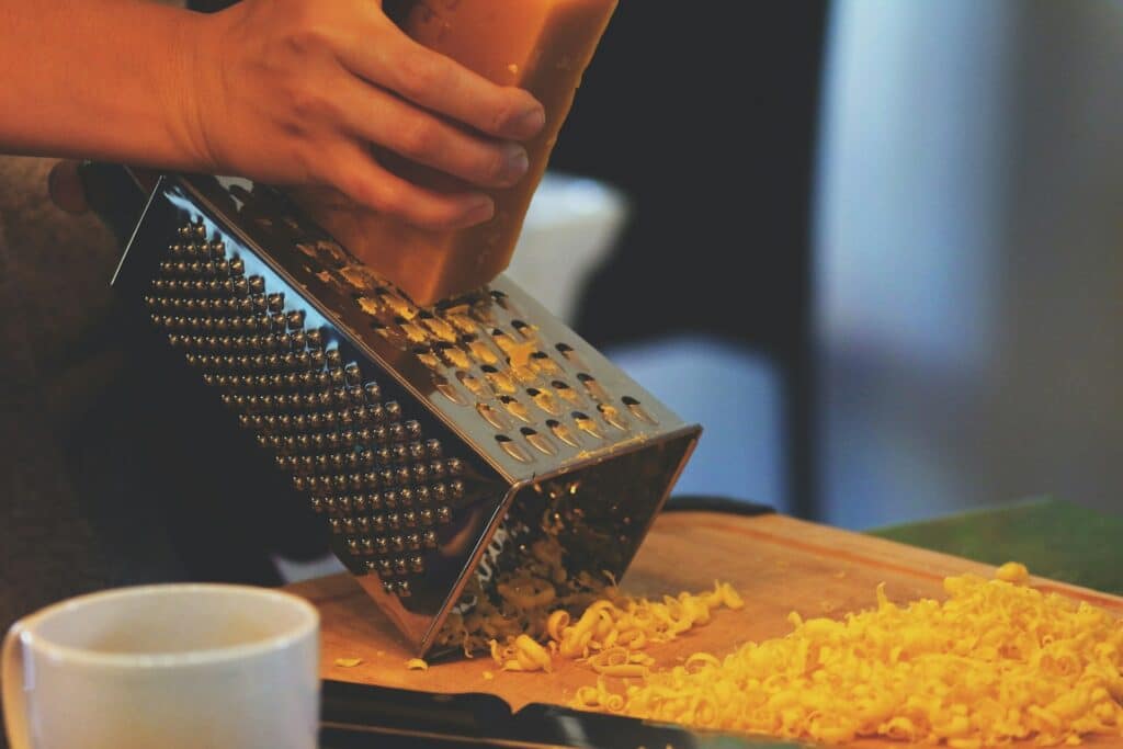 A person using a grater to grate some cheese.
