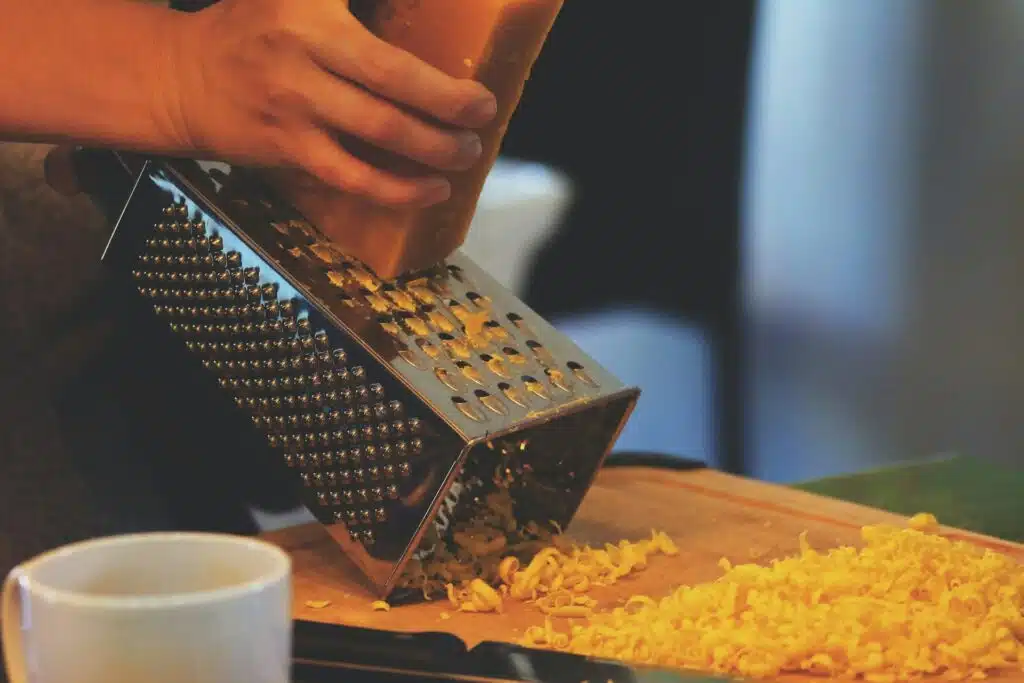 A person using a grater to grate some cheese.