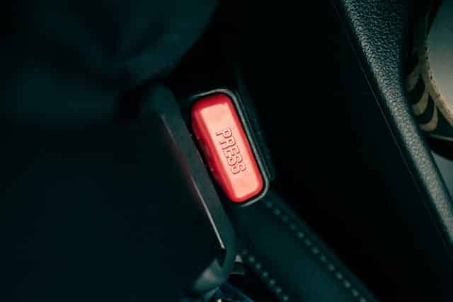 A red seatbelt release button in a driver's car.