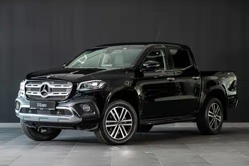 Black Mercedes-Benz X-Class pickup truck, among the best used cars, parked indoors.