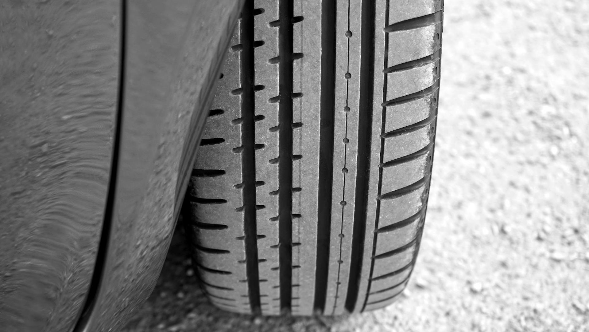 Close-up view of a car tire showing clear tread patterns on a gravel surface, illustrating why are car tyres so expensive due to their detailed design.