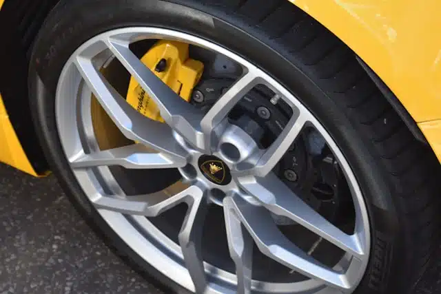 Close-up of a Lamborghini's silver wheel and yellow brake caliper, showing intricate details and car tyre tread.