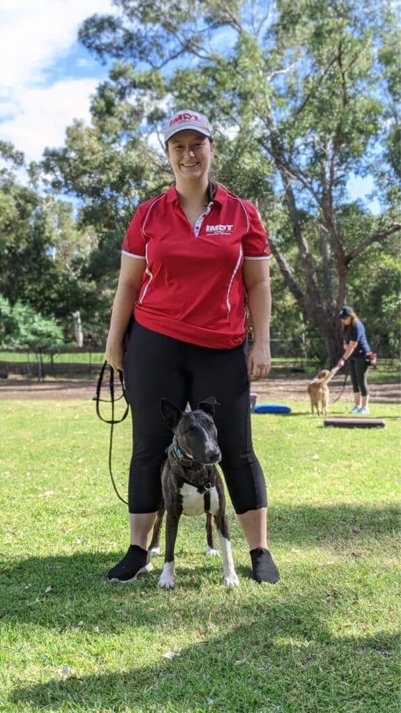 Stephanie Bryson stands in a dog training center with her dog Kira.